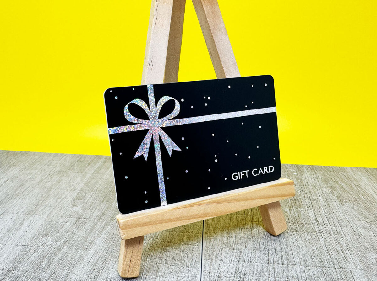 Black gift card with silver glitter bow on wooden easel
