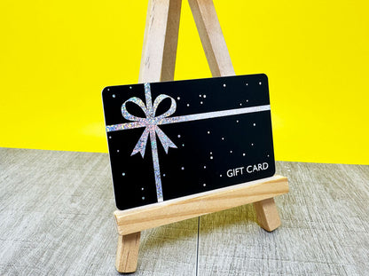 Black gift card with silver glitter bow on wooden easel